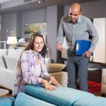adult salesman offering furniture variants to positive woman in salon