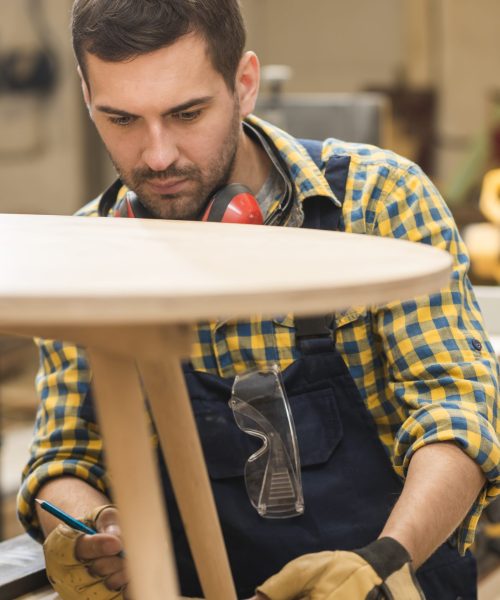 carpintero-macho-midiendo-mesa-madera-regla