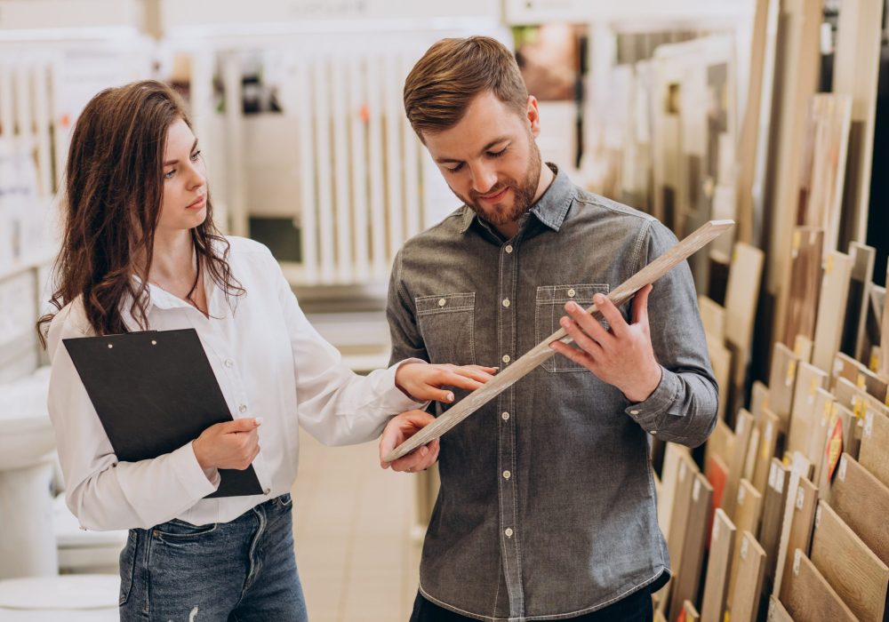 Young man with sales woman choosing tiles at building market