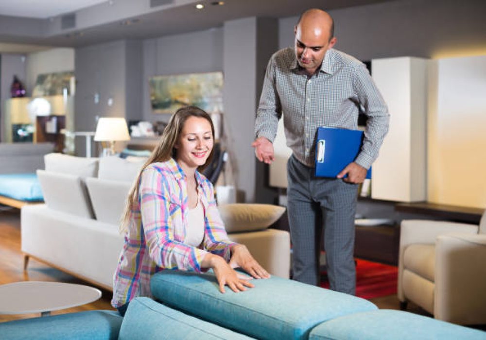 adult salesman offering furniture variants to positive woman in salon