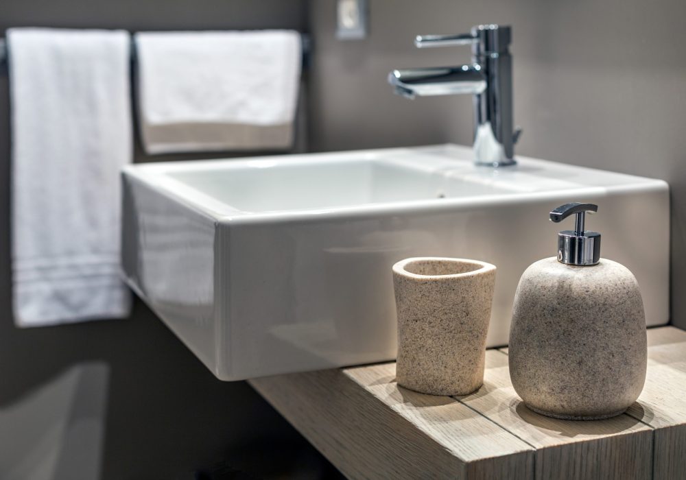 A shallow shot of a modern sink beside the bottle in the bathroom